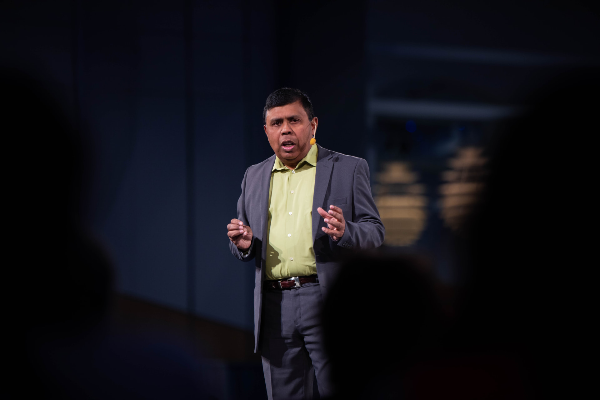 Arjun Sen speaking to a full room of business leaders, gesturing from the stage